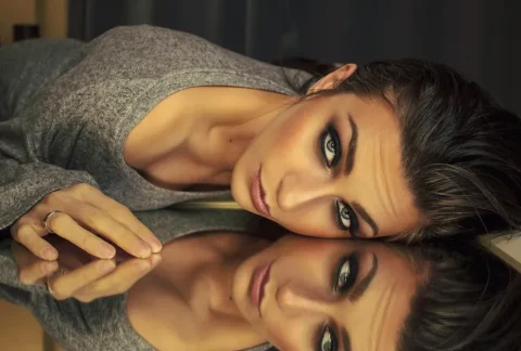 Femme maquillée allongée contre un miroir