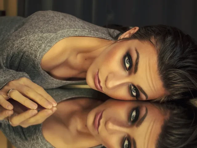 Femme maquillée allongée contre un miroir