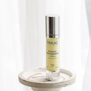 Flacon d'Emulsion Séborégulatrice jaune posé debout sur une table