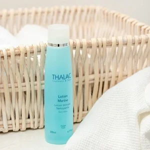 Flacon bleu de lotion marine devant un panier en osier