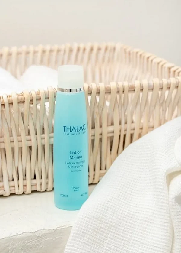 Flacon bleu de lotion marine devant un panier en osier