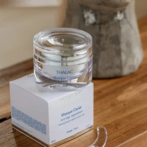 Pot transparent de masque caviar anti-age posé sur sa boite en carton blanche