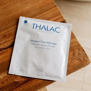 Sachet de masque tissu anti-âge sur une planche de bois vernis