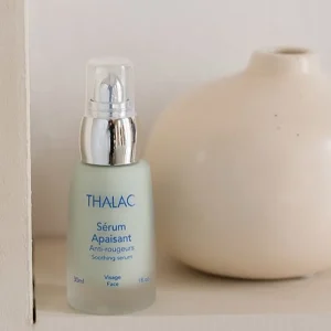 Flacon de sérum apaisant turquoise à côté d'un vase