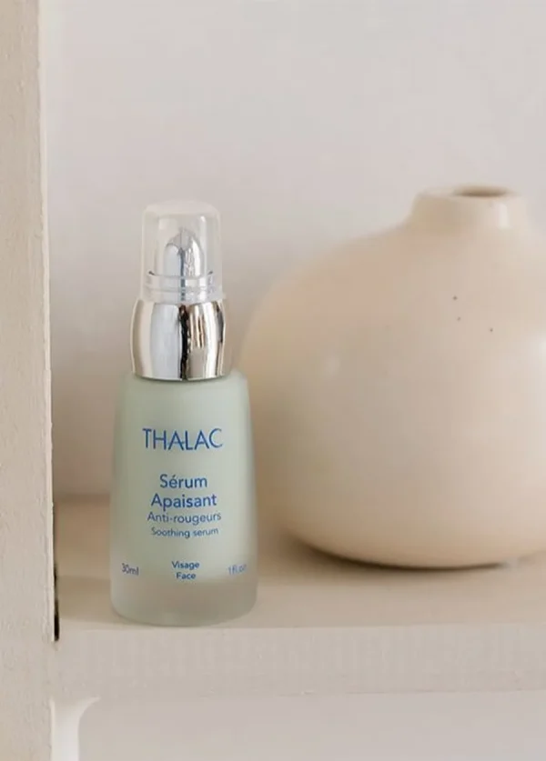 Flacon de sérum apaisant turquoise à côté d'un vase
