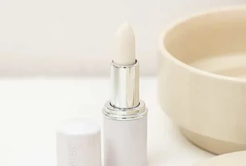 Stick à lèvre débouché avec le bouchon à côté posé au bord dans une salle de bain