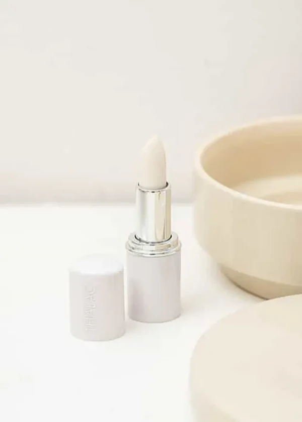 Stick à lèvre débouché avec le bouchon à côté posé au bord dans une salle de bain