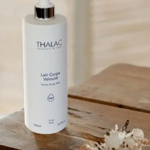 Flacon pousse-pousse blanc de lait corps velouté sur une table en bois