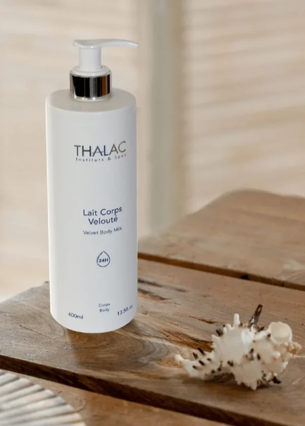 Flacon pousse-pousse blanc de lait corps velouté sur une table en bois