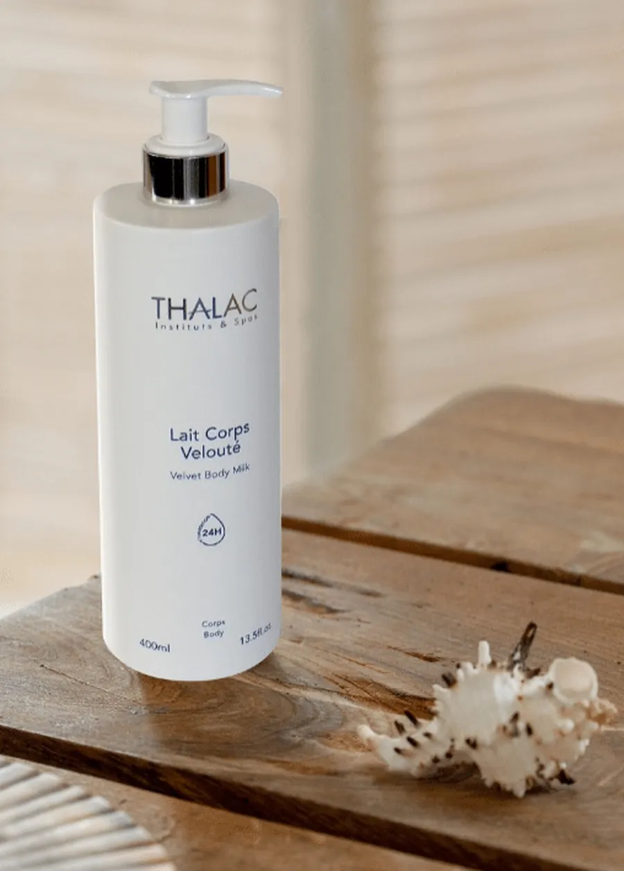 Flacon pousse-pousse blanc de lait corps velouté sur une table en bois