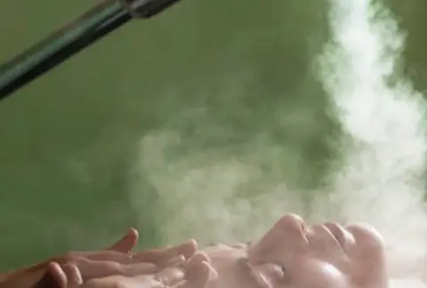 visage sous de la vapeur avec un jet de brume sur fond vert