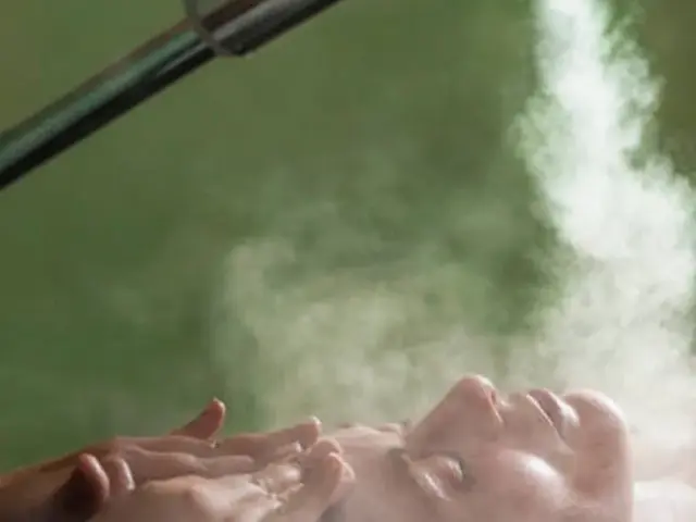 visage sous de la vapeur avec un jet de brume sur fond vert