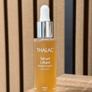 Flacon jaune de Sérum Liftant posé sur une table en bois