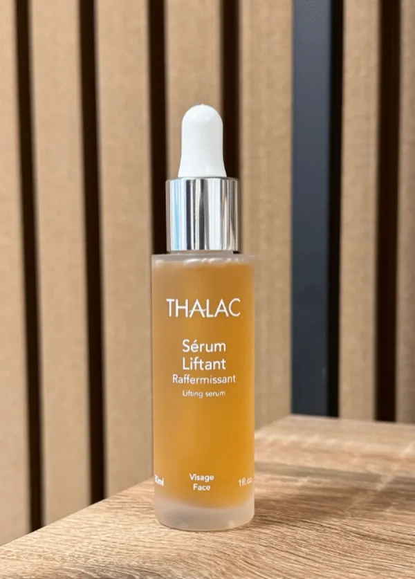 Flacon jaune de Sérum Liftant posé sur une table en bois