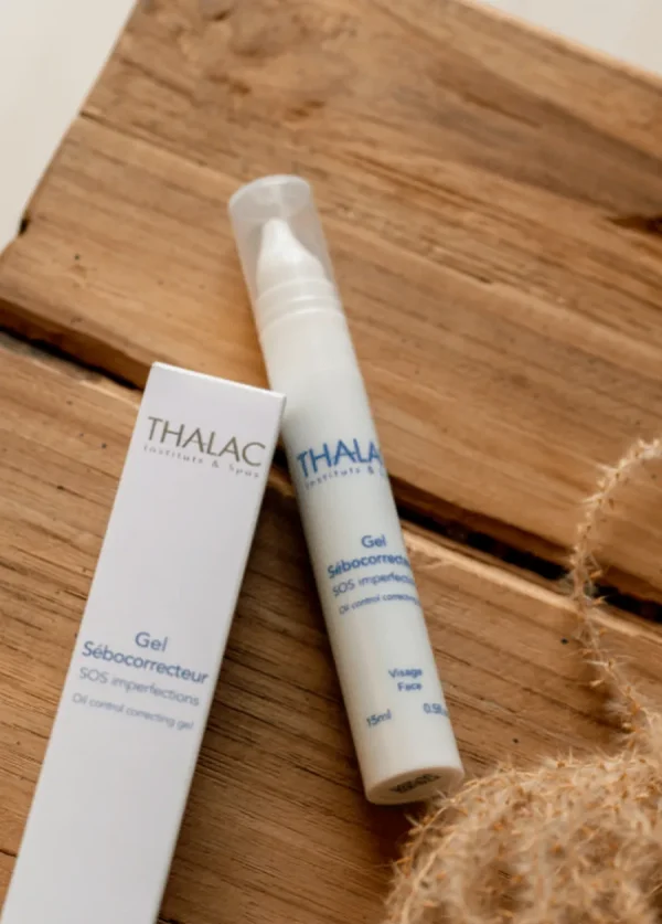 Flacon de gel sébocorrecteur allongé sur un table à côté de sa boite en carton blanche