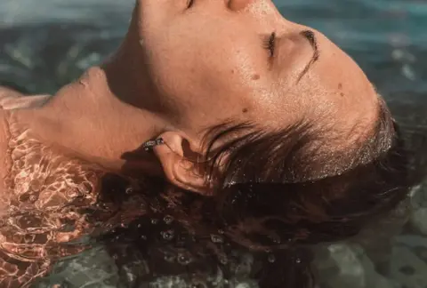 Visage de femme les yeux fermés les cheveux dans de l'eau claire