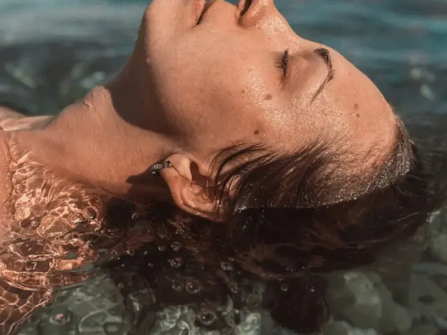 Visage de femme les yeux fermés les cheveux dans de l'eau claire