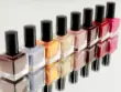 huit pots de vernis classiques avec bouchons noir en ordre de couleurs alignés