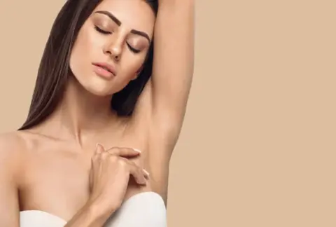 Femme brune levant le bras gauche et présentant une aisselle épilée