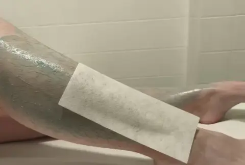 jambes enduites de cire verte avec une bande blanche dessus