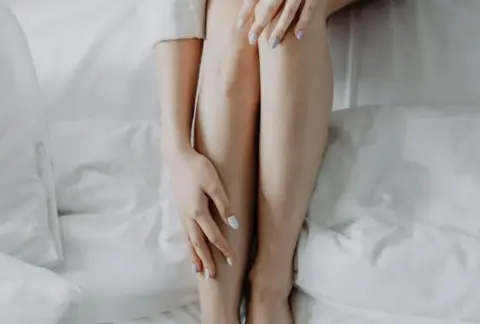 femme vue du dessus en chemisier blanc avec les jambes collées épilées
