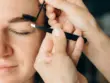 visage de femme avec deux mains travaillant le sourcil au dessus d'un oeil fermé