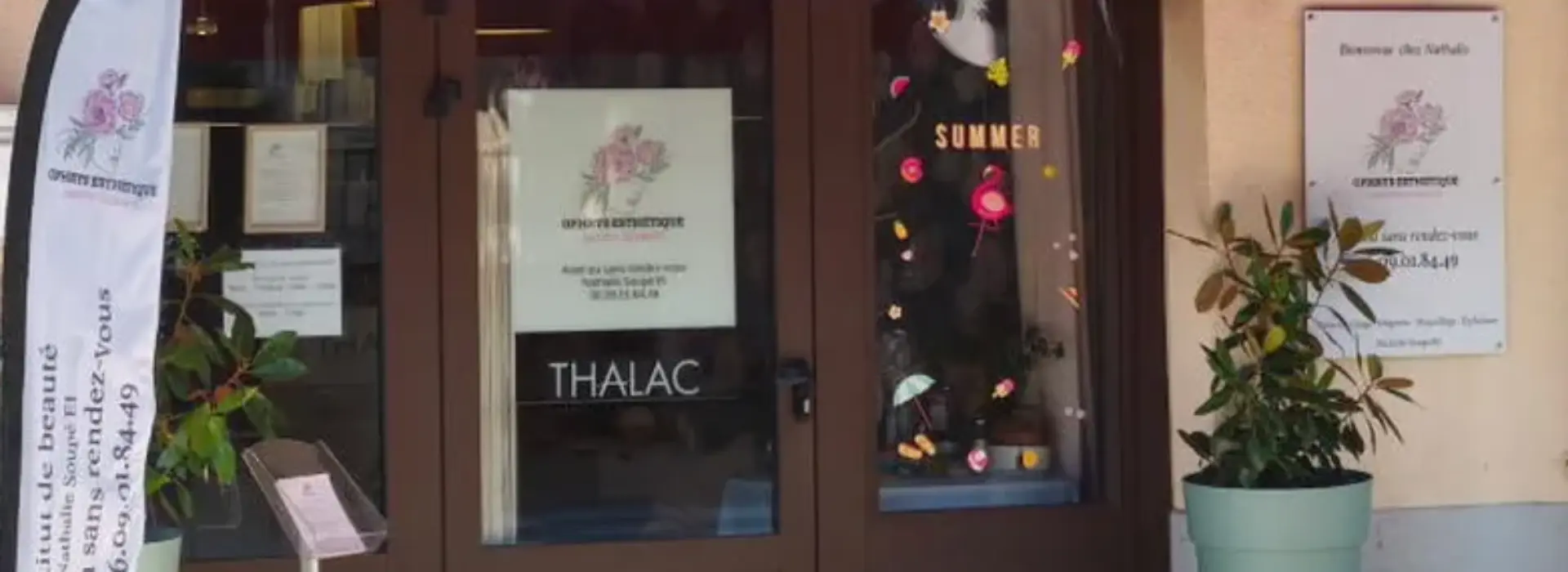 Rue avec vitrine de la boutique avec deux pots de fleurs sur les côtés et un haut-vent rouge