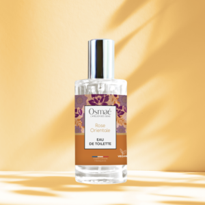 Flacon de rose orientale avec bouchon argenté sur fond ocre