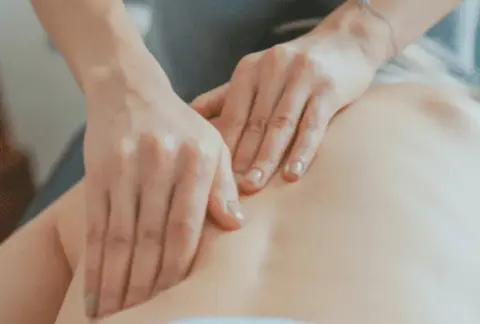 deux mains massant un dos allongé